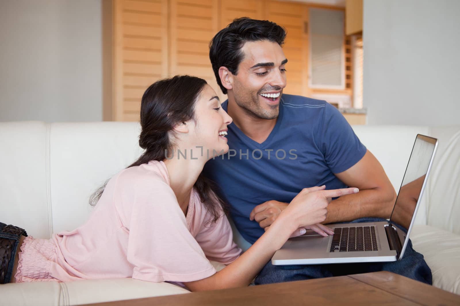Laughing young couple using a laptop in their living room