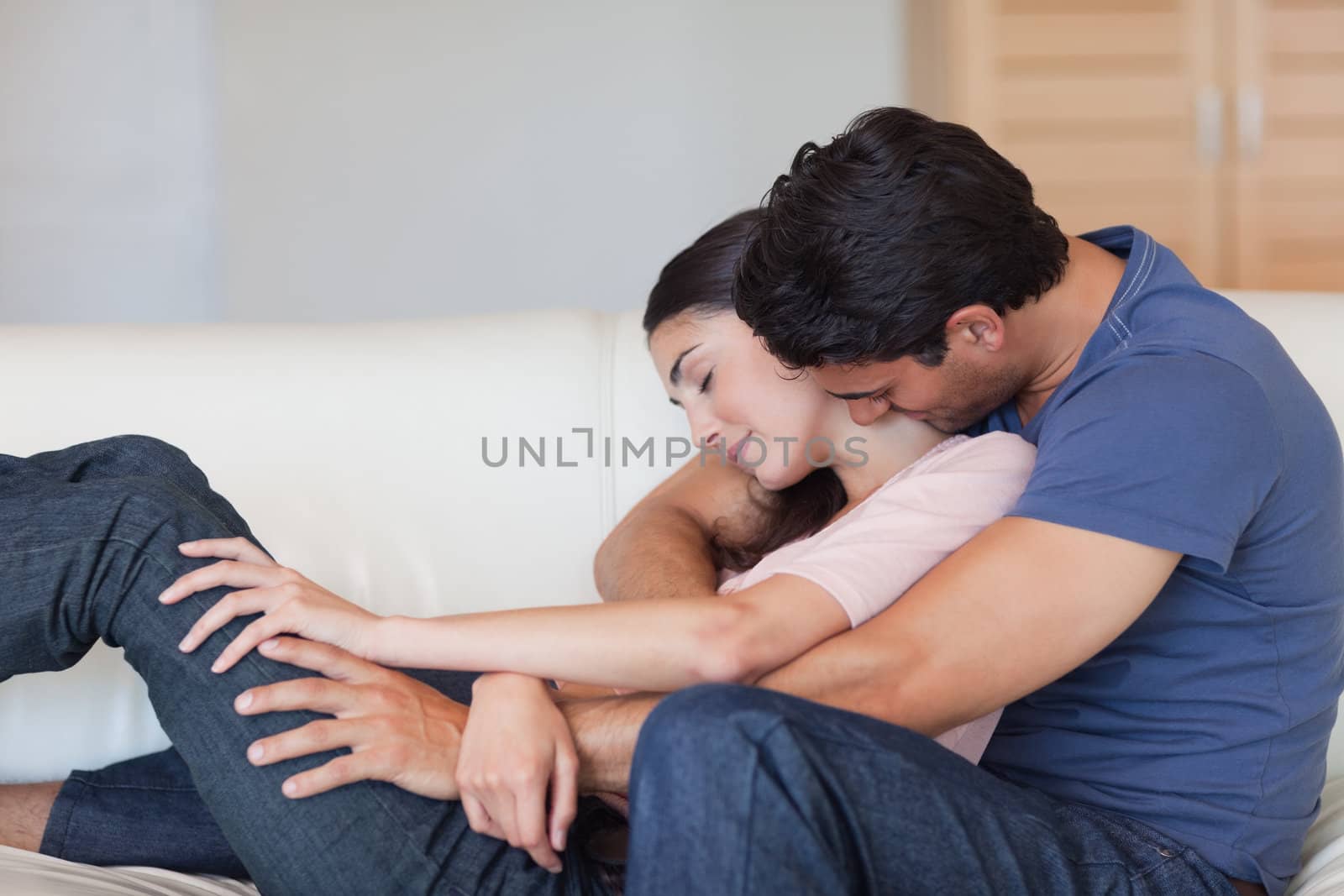 Man kissing his wife in the neck in their living room