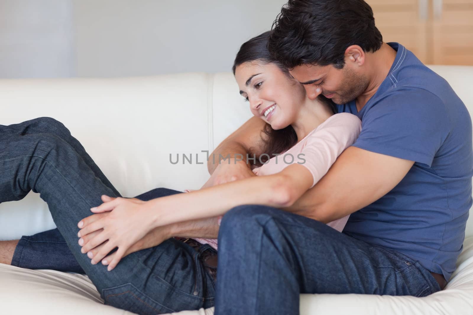Man kissing his girlfriend in the neck in their living room