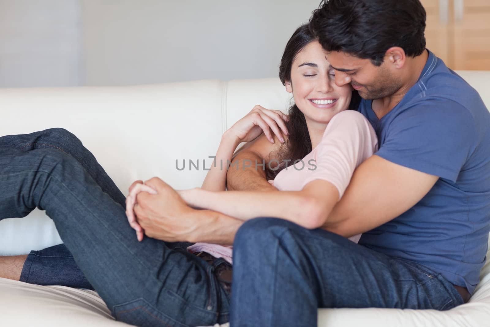 Man kissing his fiance in the neck in their living room