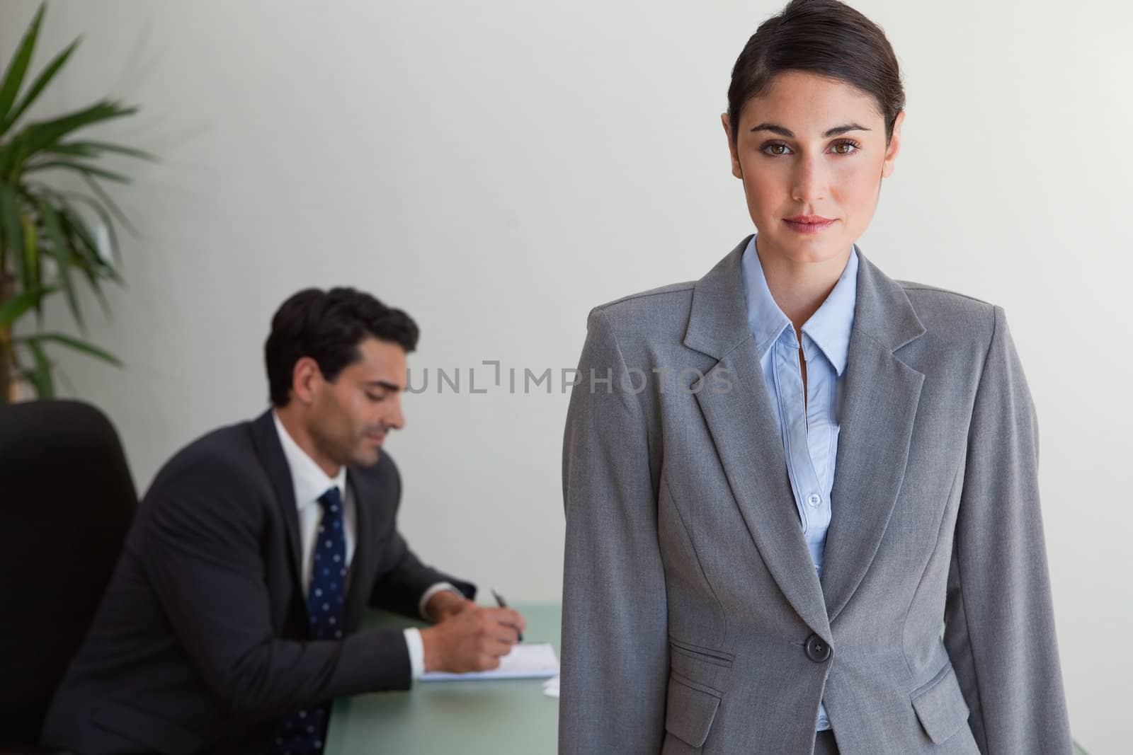 Gorgeous businesswoman posing while her colleague is working in an office
