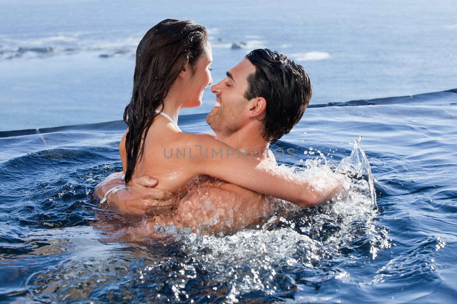 Joyful couple cuddling each other in a swimming pool