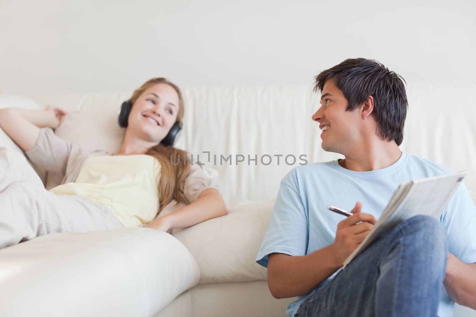 Man doing crosswords while his girlfriend is listening to music in their living room