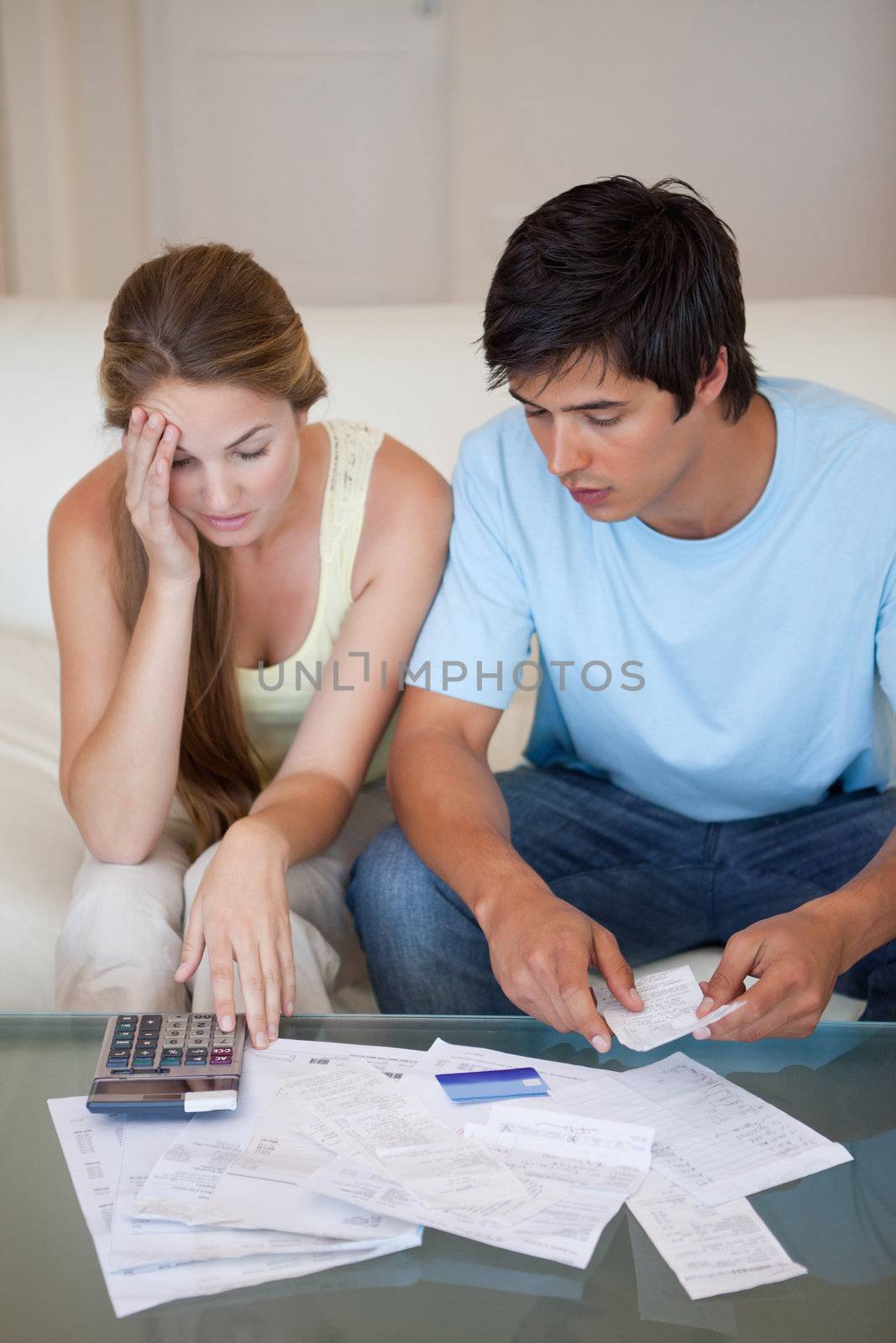 Portrait of a worried couple looking at their bills in their living room