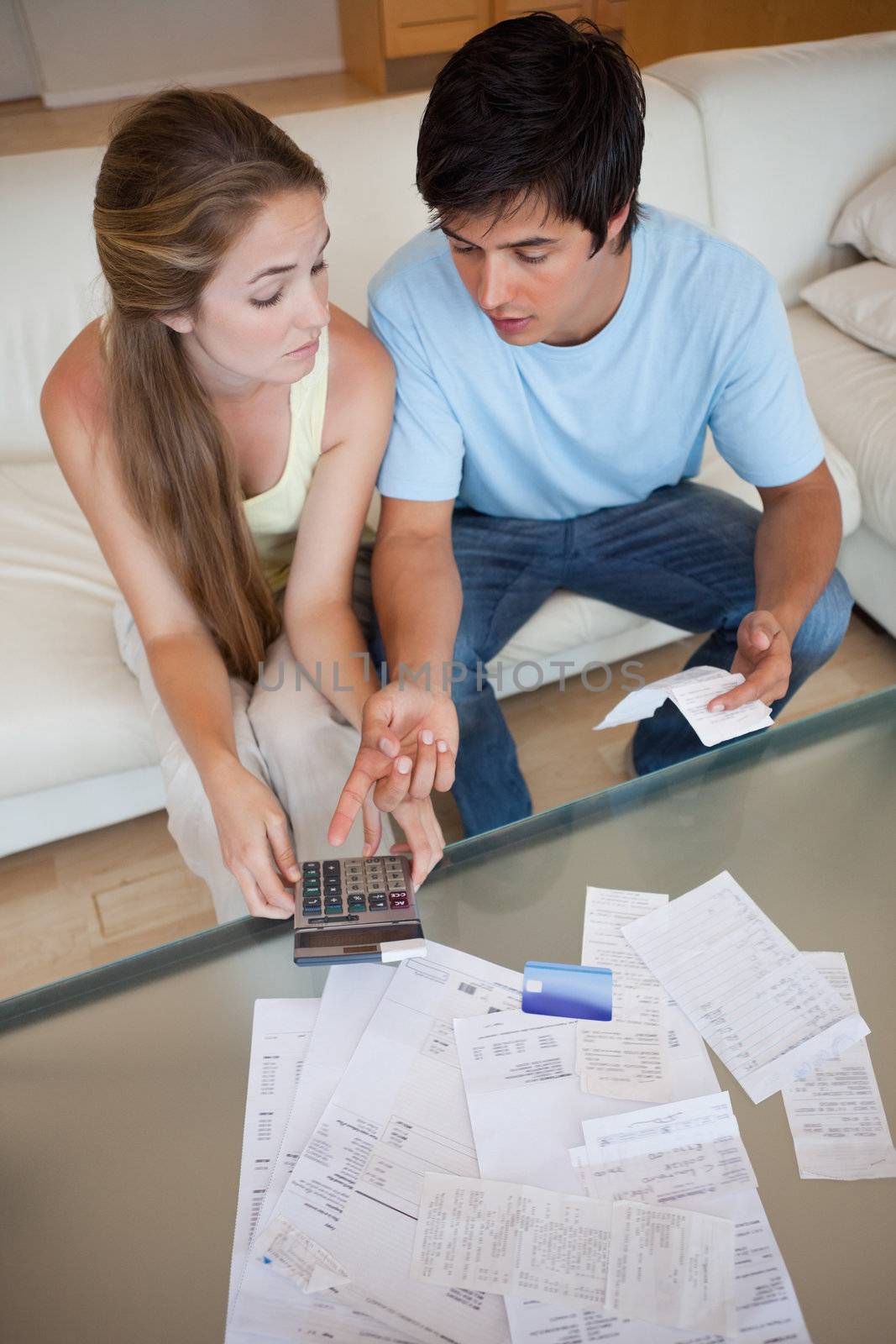 Portrait of a sad couple looking at their receipts in their living room