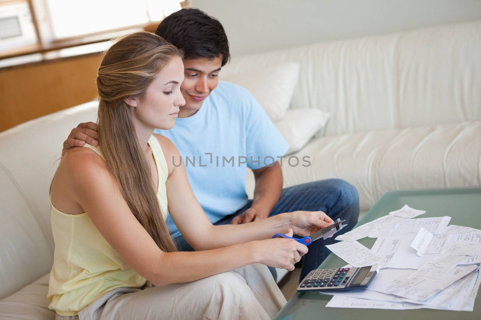 Young couple cutting their credit card in their living room