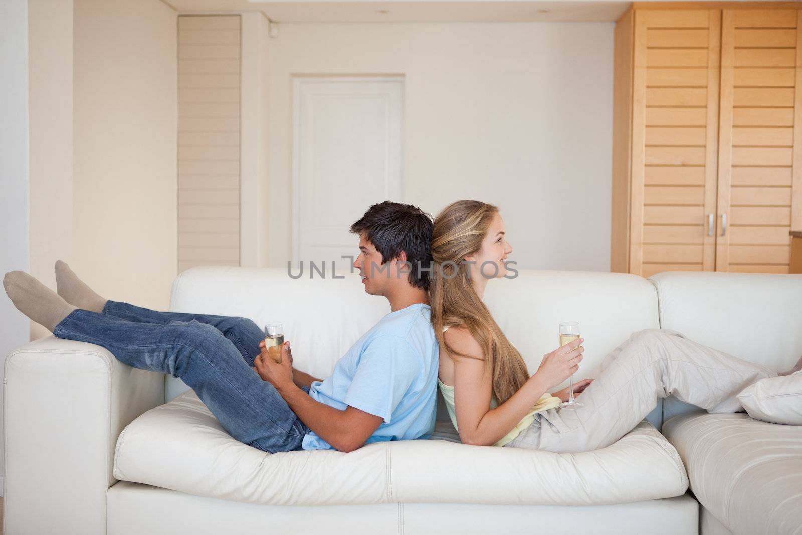 Couple sitting back to back with a glass of wine in their living room