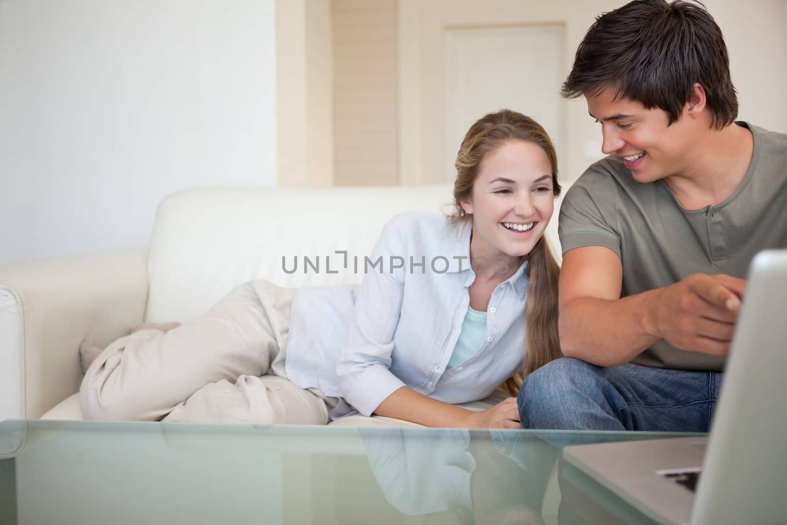 Laughing couple using a notebook in their living room