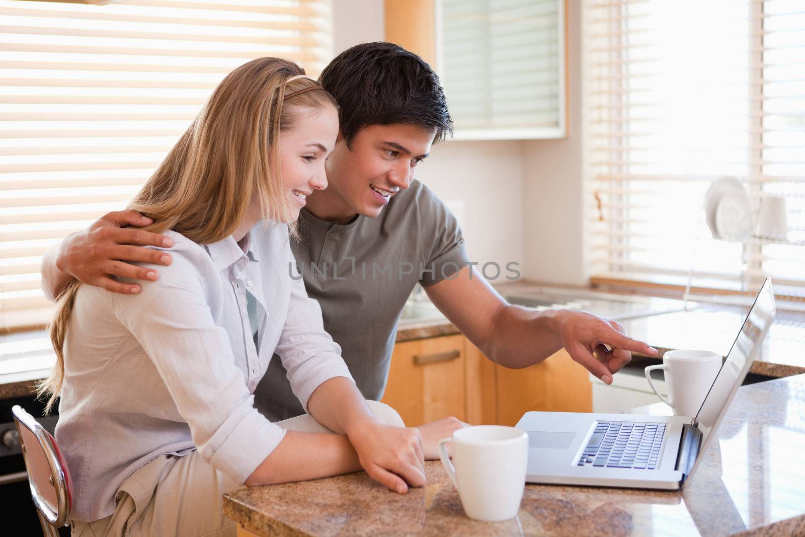 Couple having coffee while using a laptop in their kitchen