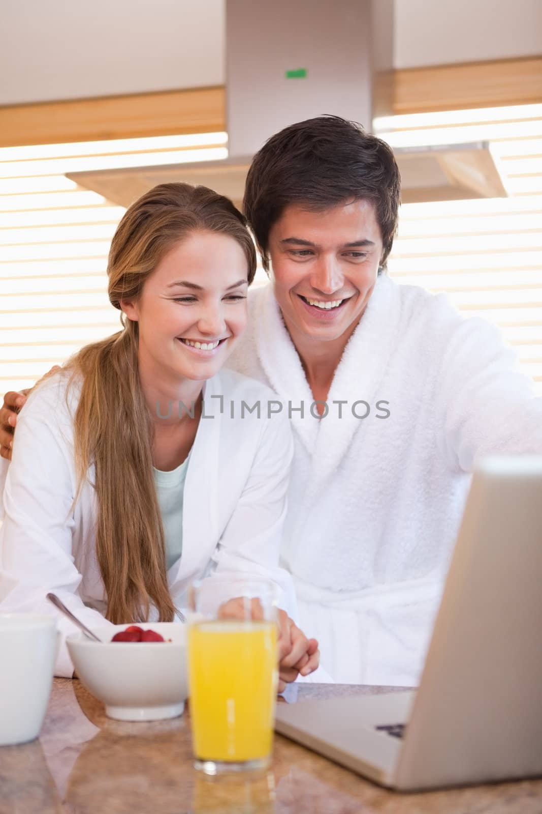 Portrait of a couple having breakfast while using a notebook in their kitchen