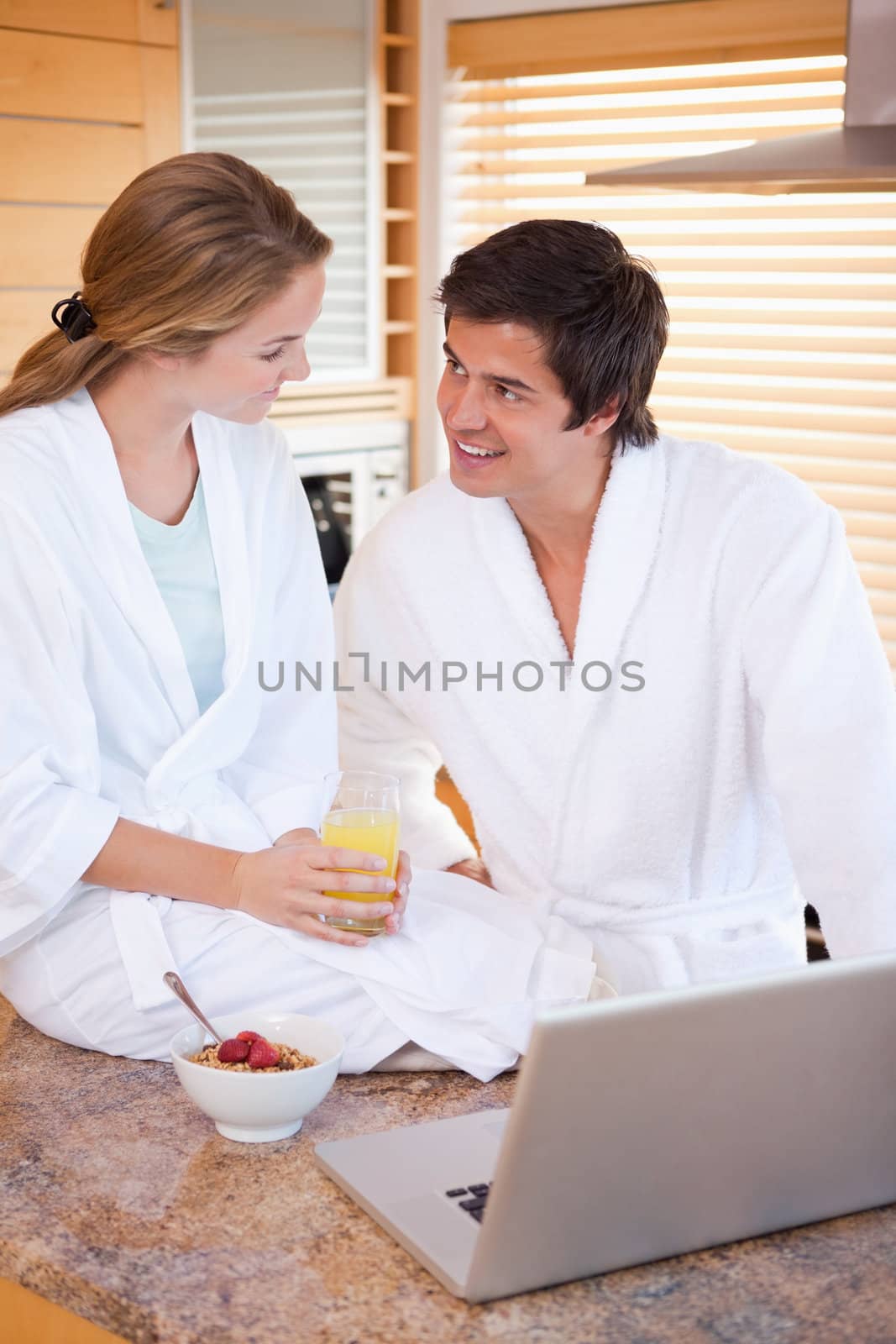 Portrait of a lovely couple having breakfast while using a notebook in their kitchen