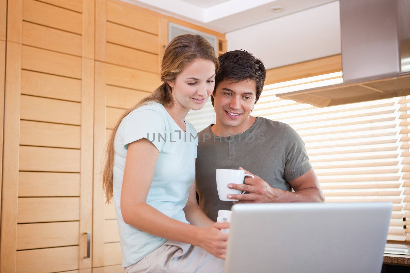 Couple having tea while using a notebook in their kitchen
