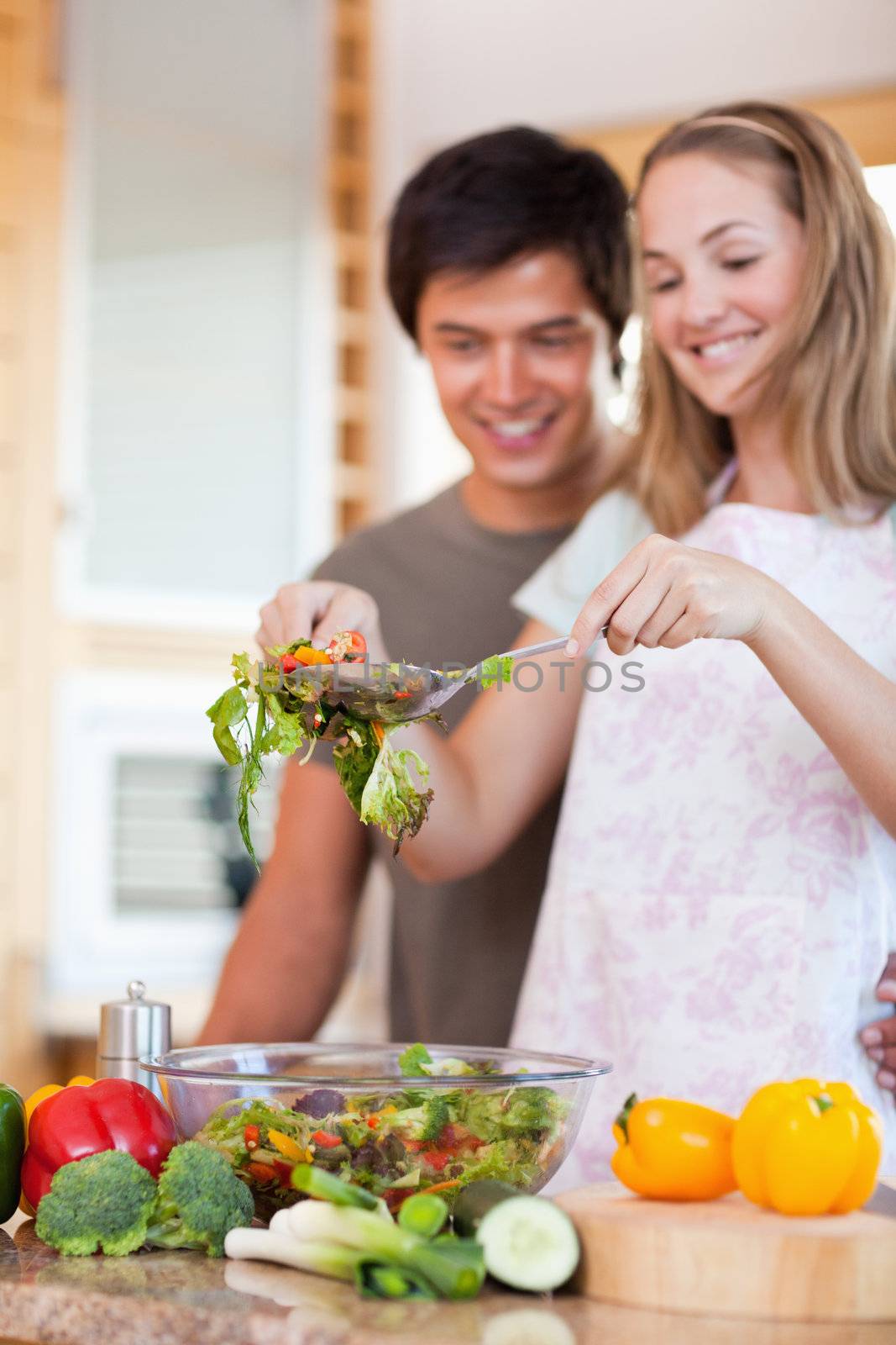 Portrait of a young couple making a salad in their kitchen