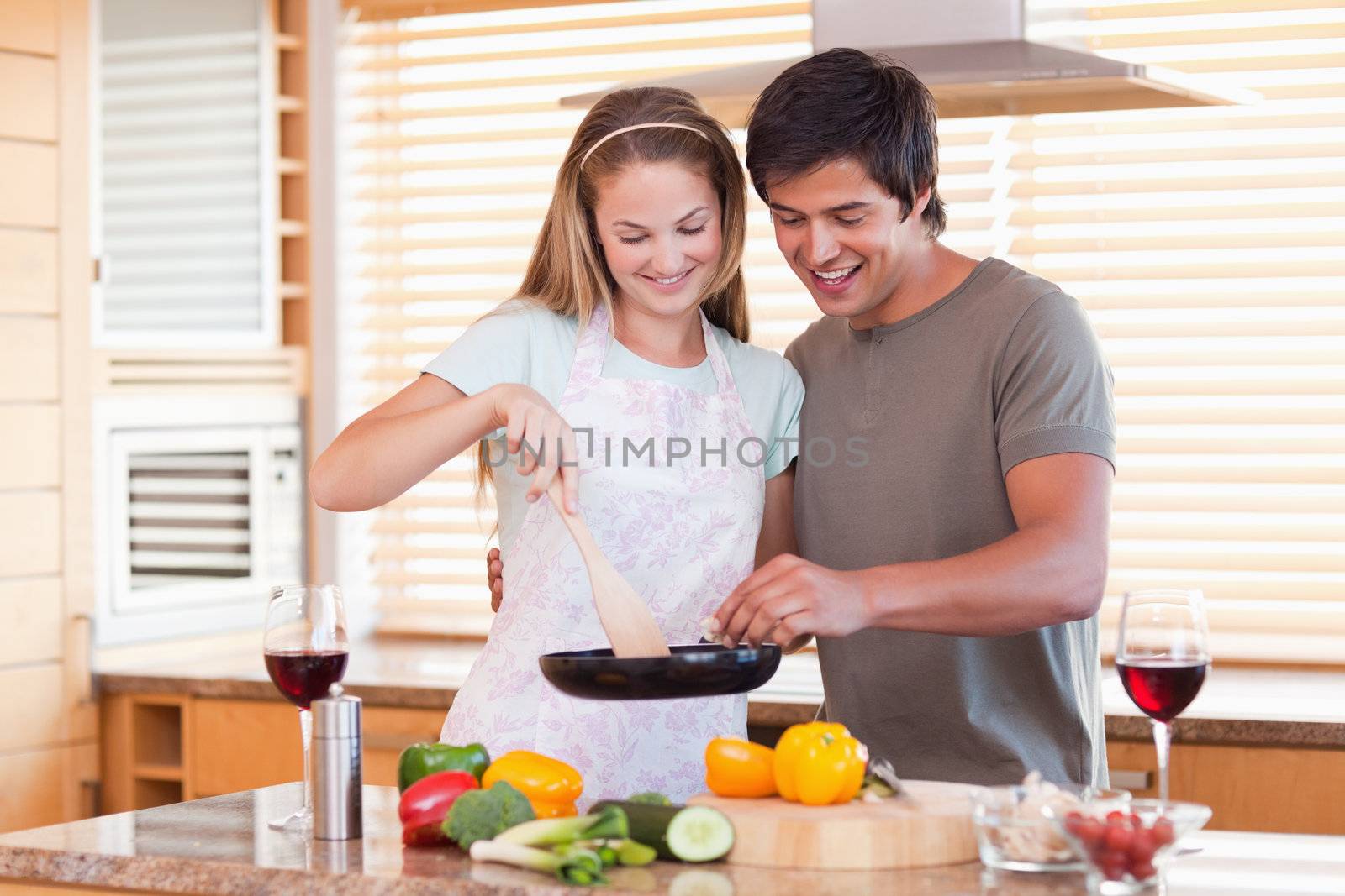 Couple cooking dinner while drinking red wine in their kitchen