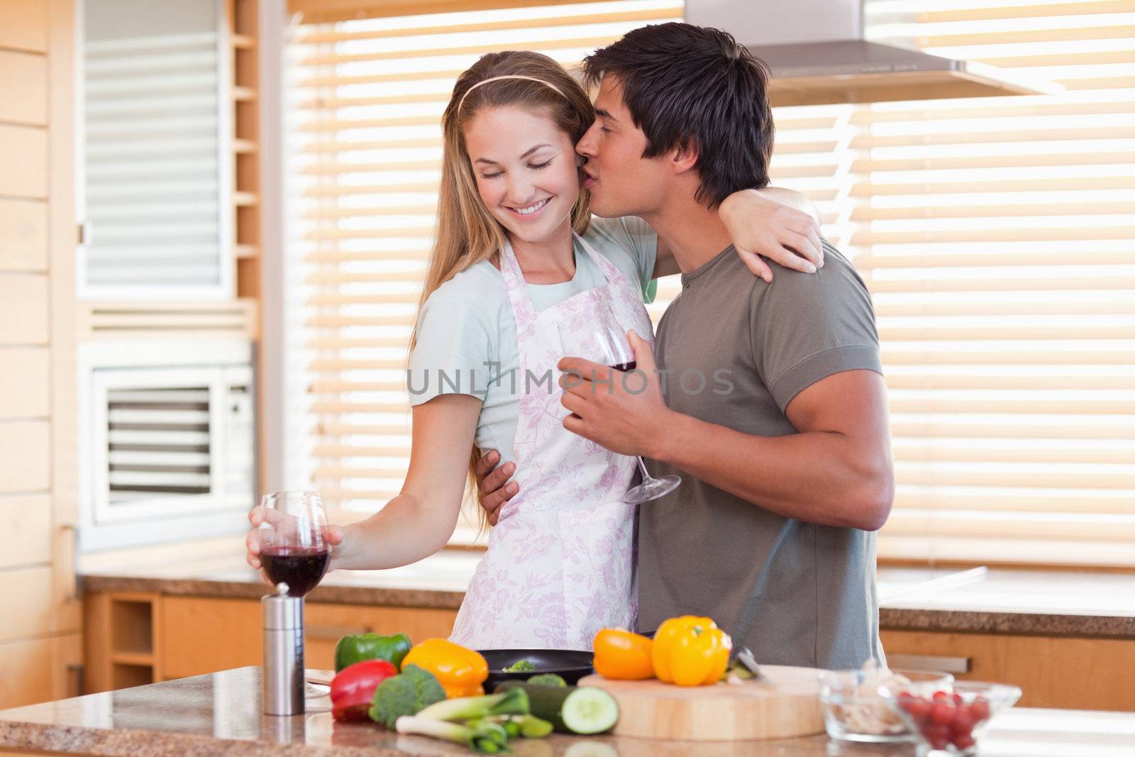 Lovely couple drinking wine while kissing in their kitchen