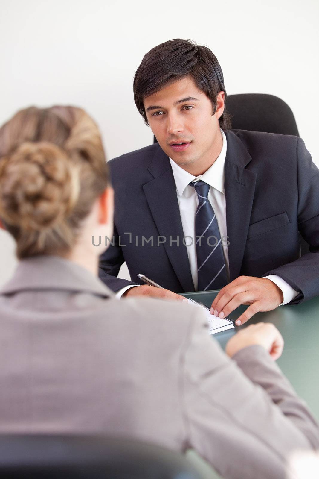 Portrait of a serious manager interviewing a female applicant in his office