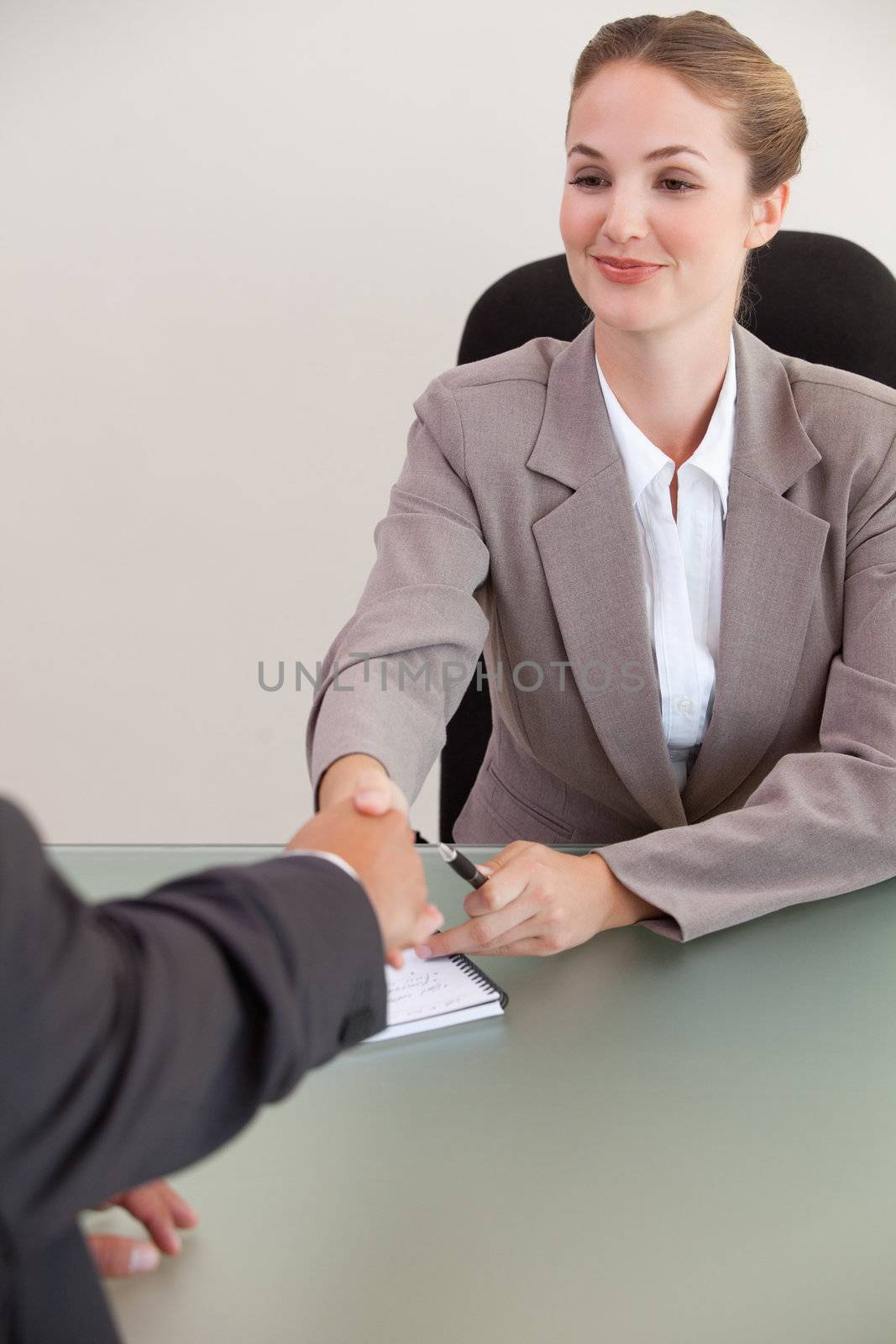Portrait of a young manager shaking the hand of a customer in her office