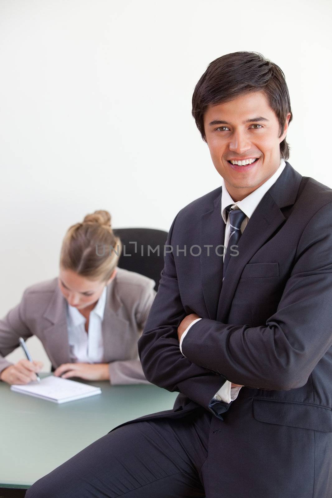 Portrait of an office worker posing while his colleague is working in an office