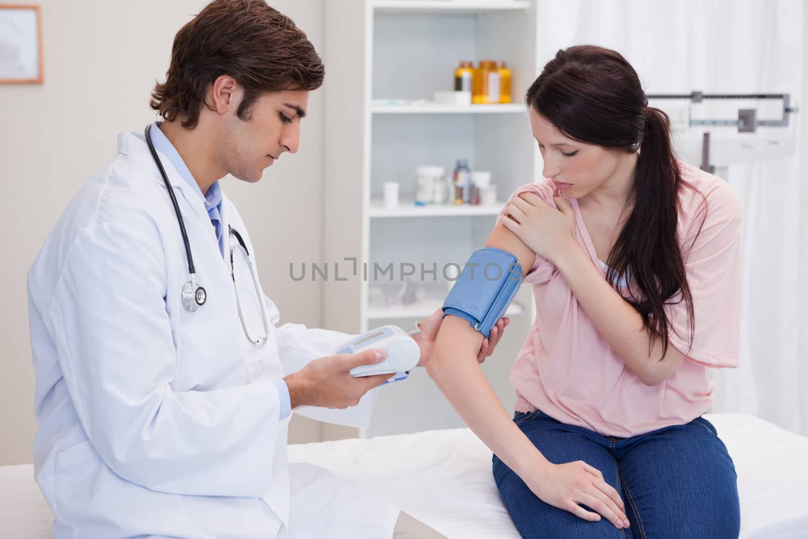 Young doctor taking patients blood pressure