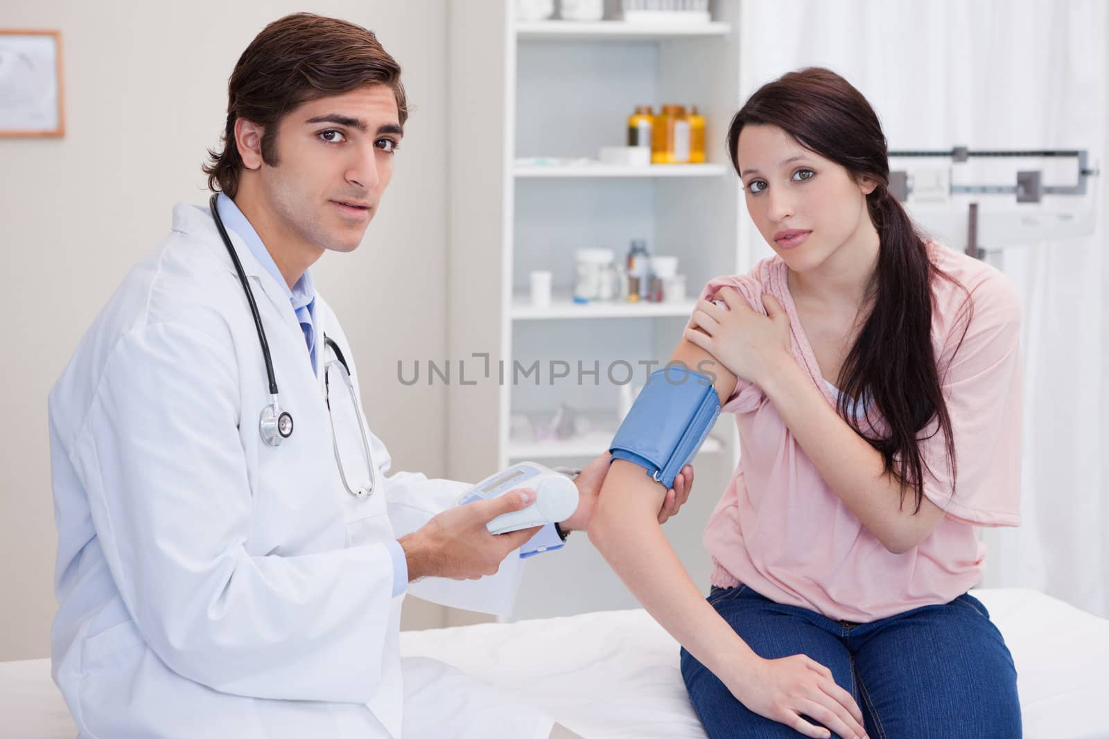 Doctor taking young female patients blood pressure