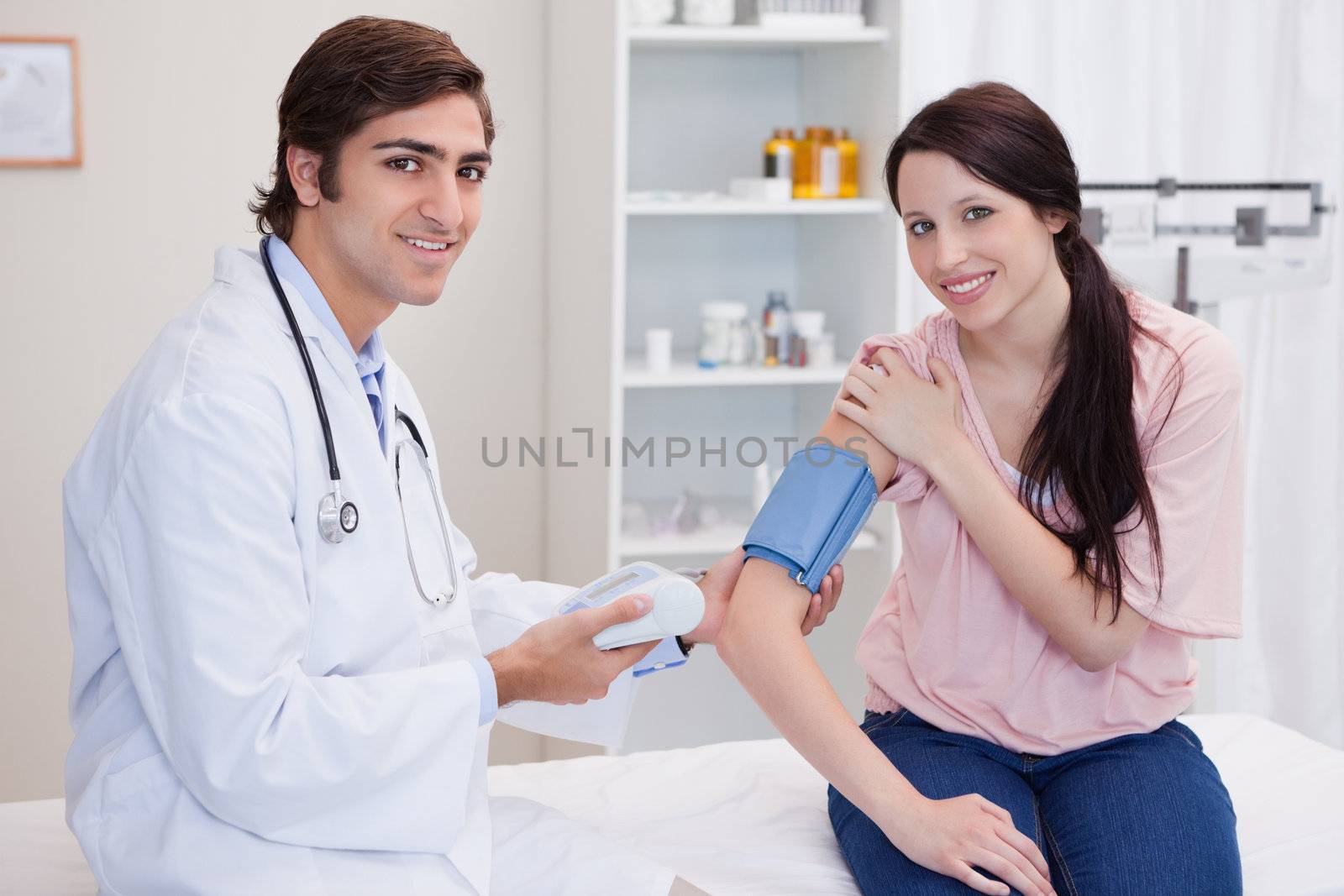 Smiling male doctor taking patients blood pressure