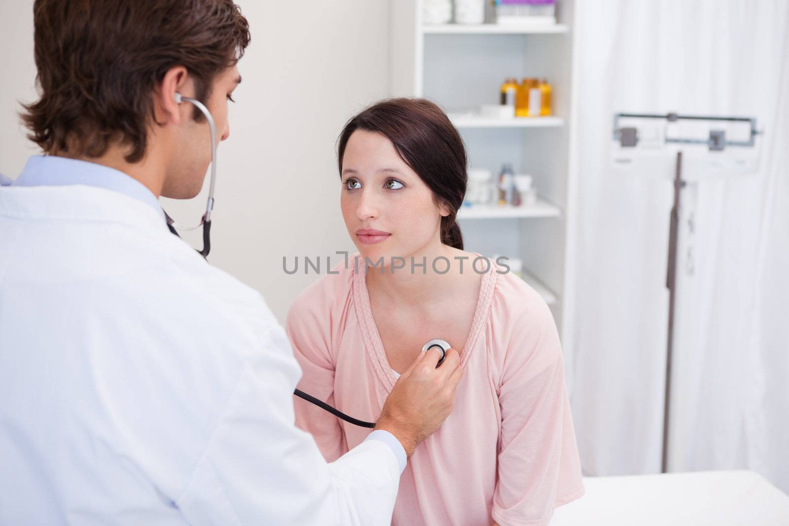Young male doctor taking his patients heart beat