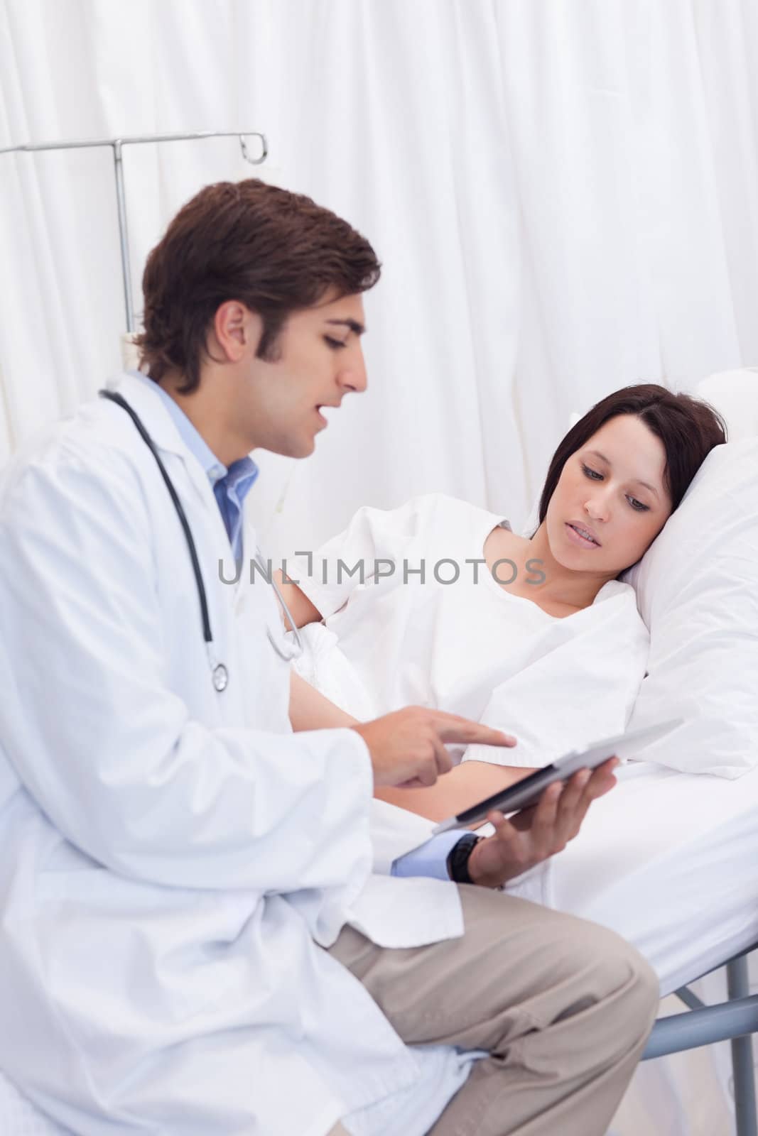 Young doctor showing his patient whats on his tablet