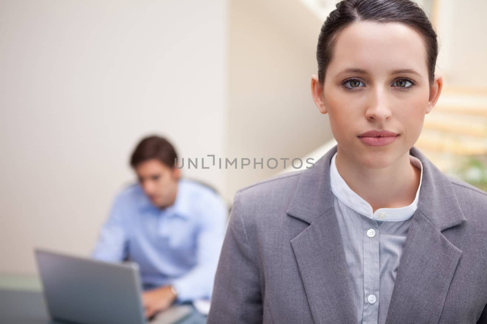 Young businesswoman with colleague on his laptop behind her