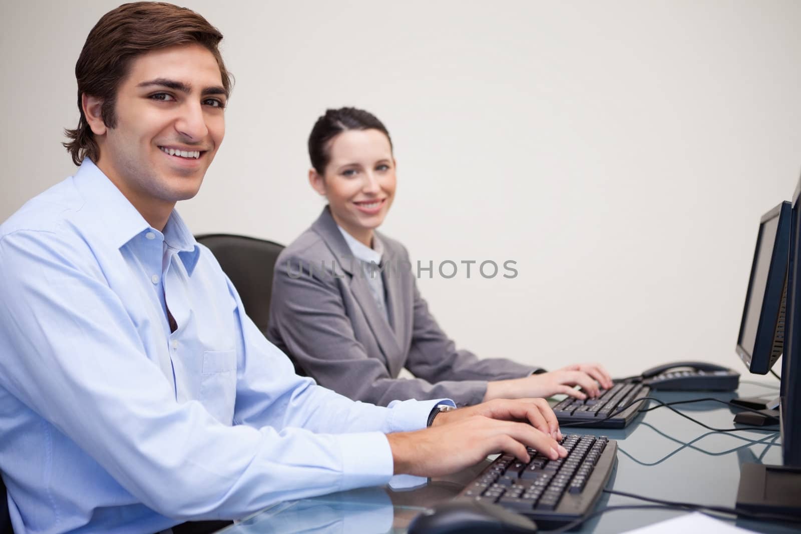 Side view of smiling young colleagues working next to each other