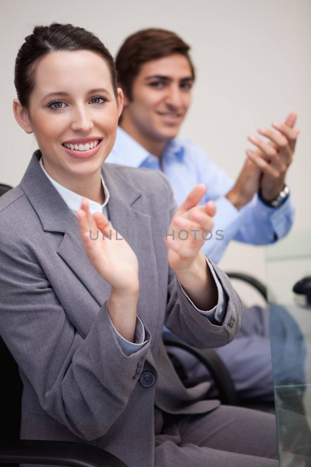 Side view of clapping young business team sitting at darkness