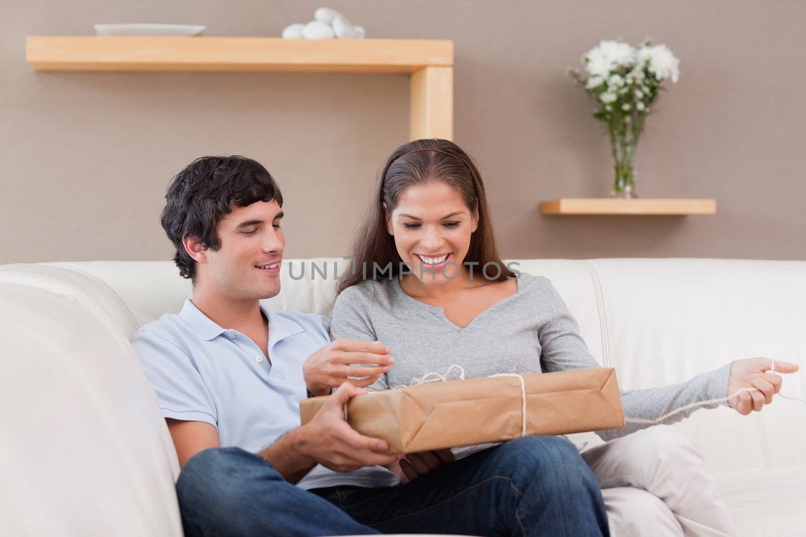 Young couple opening parcel on the sofa