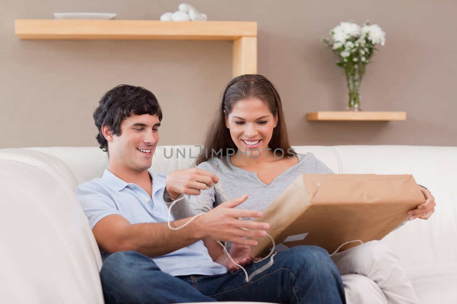 Young couple opening parcel on the couch