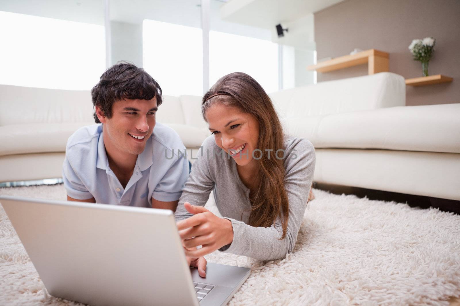 Young couple with laptop on the carpet