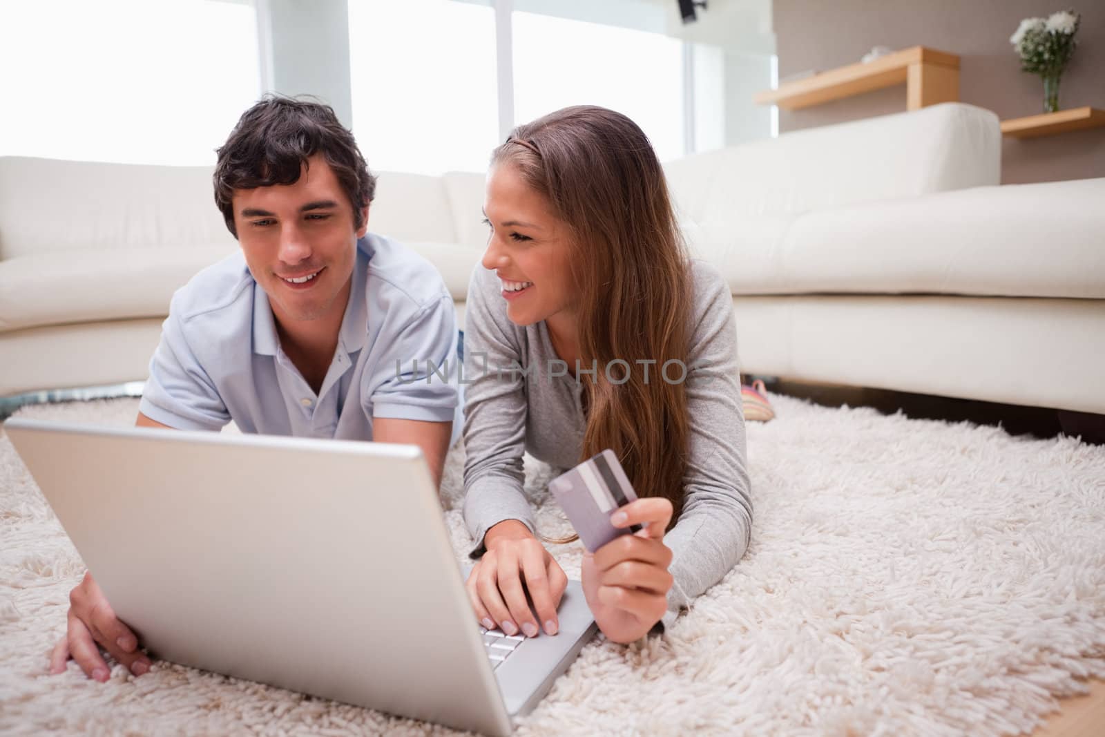 Young couple lying on the floor shopping online