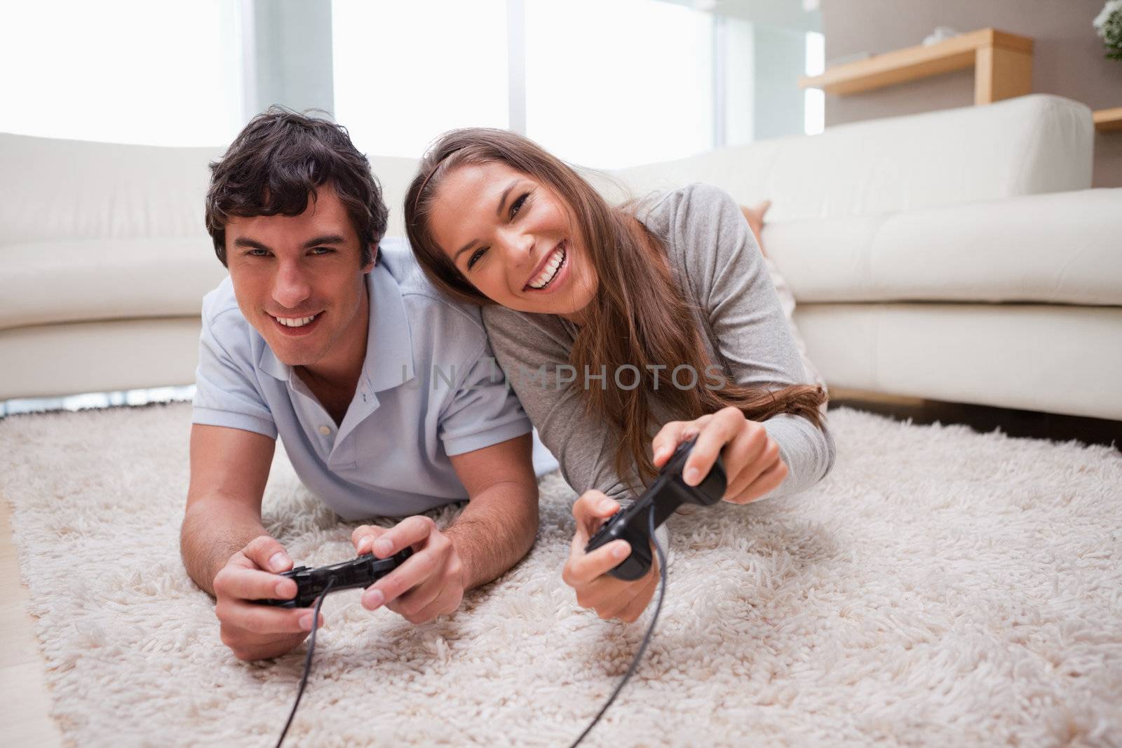 Young couple playing video games on the floor