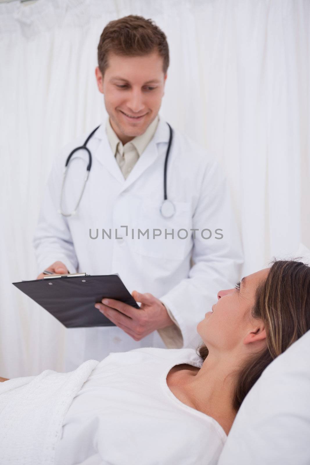 Doctor with clipboard talking with bedridden patient