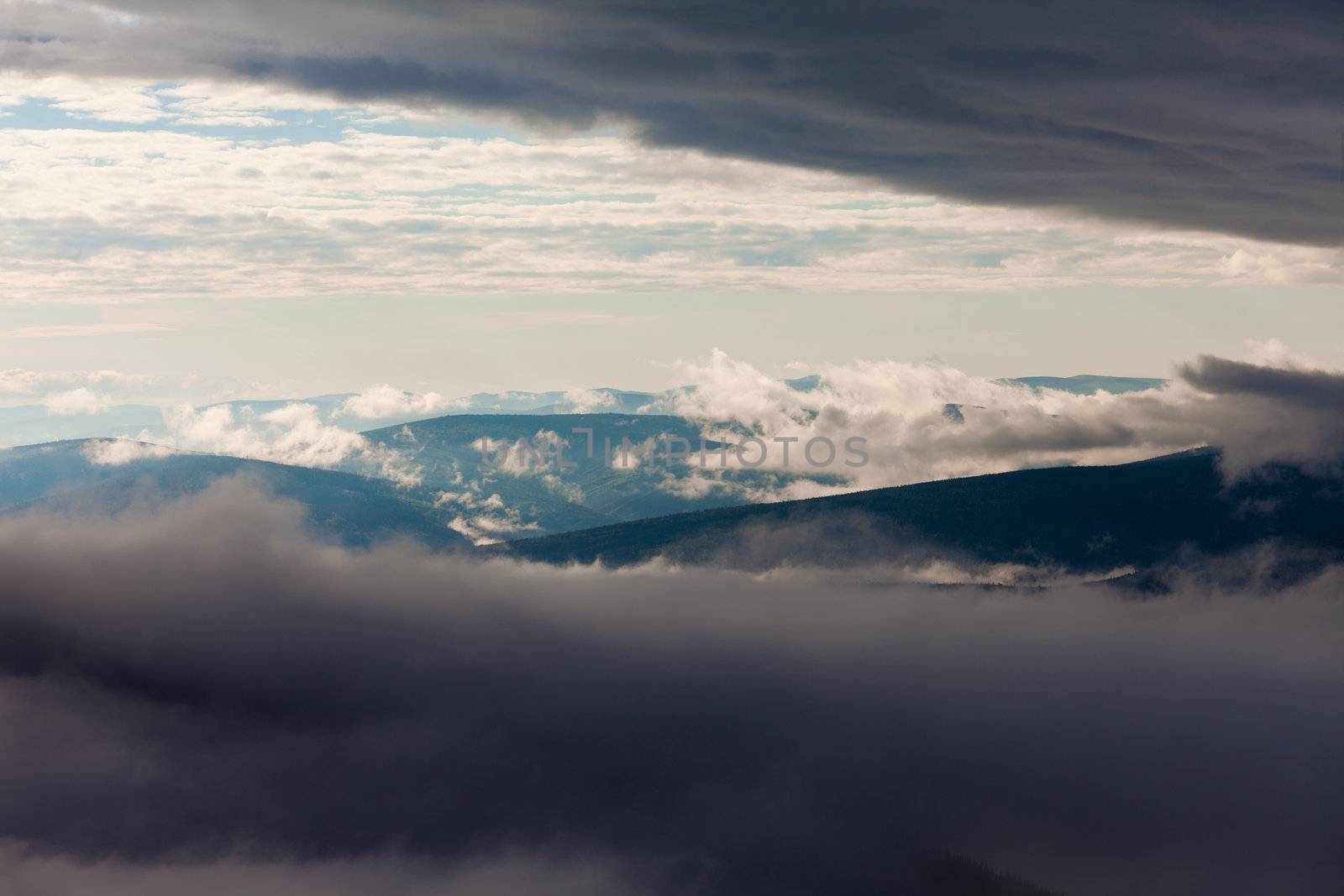 Clouds billowing over and between hills and mountains nature landscape.