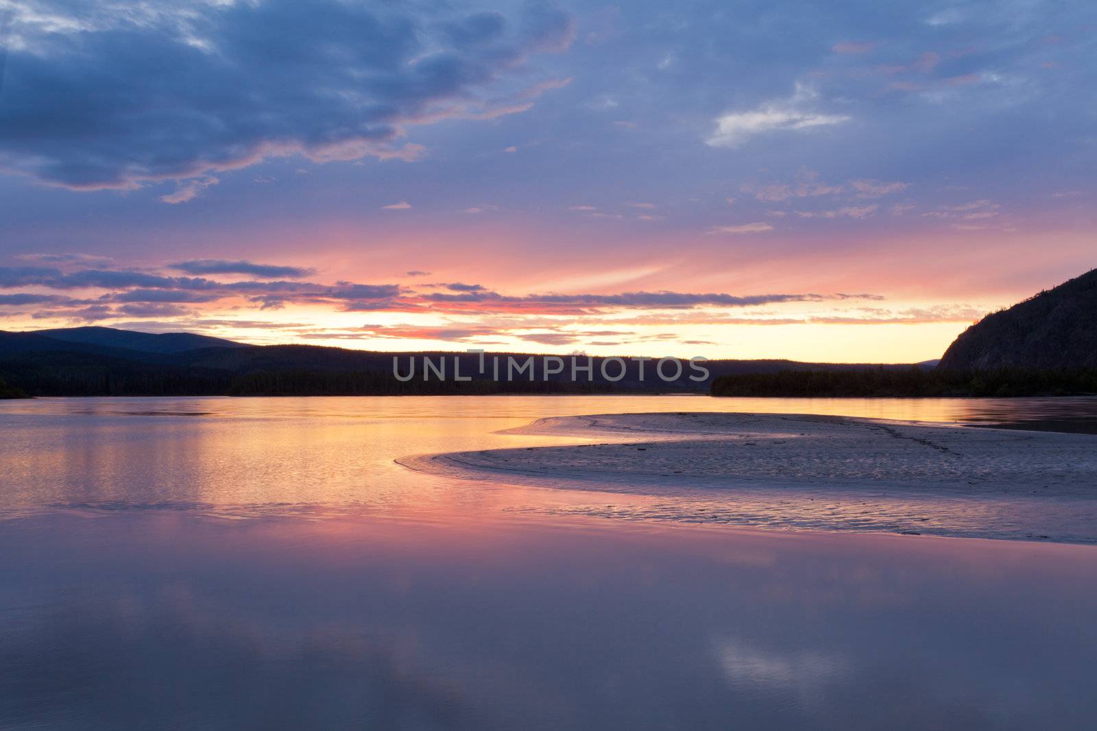 Beautiful sunset over wilderness of Yukon River, Yukon Territory, Canada, near Dawson City forming a northern riverscape.