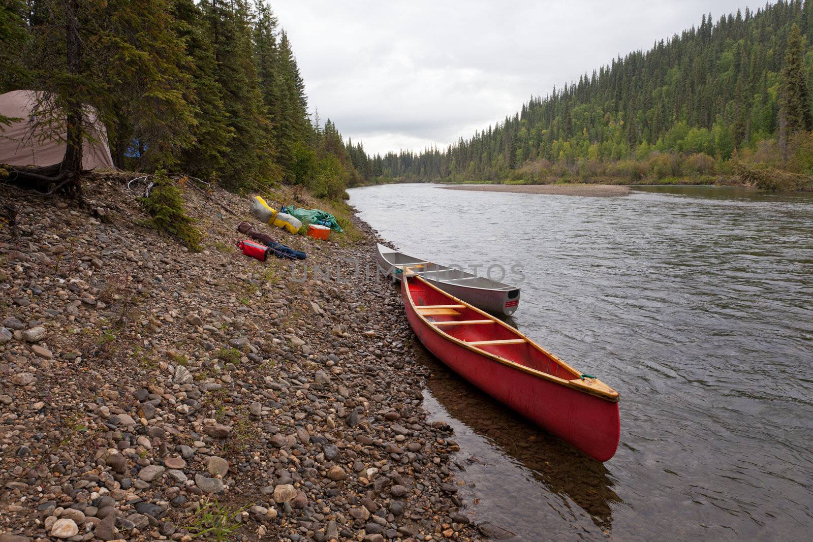 Tent camp in boreal forest and canoes on paddle river trip on McQuesten River, Yukon Territory, Canada