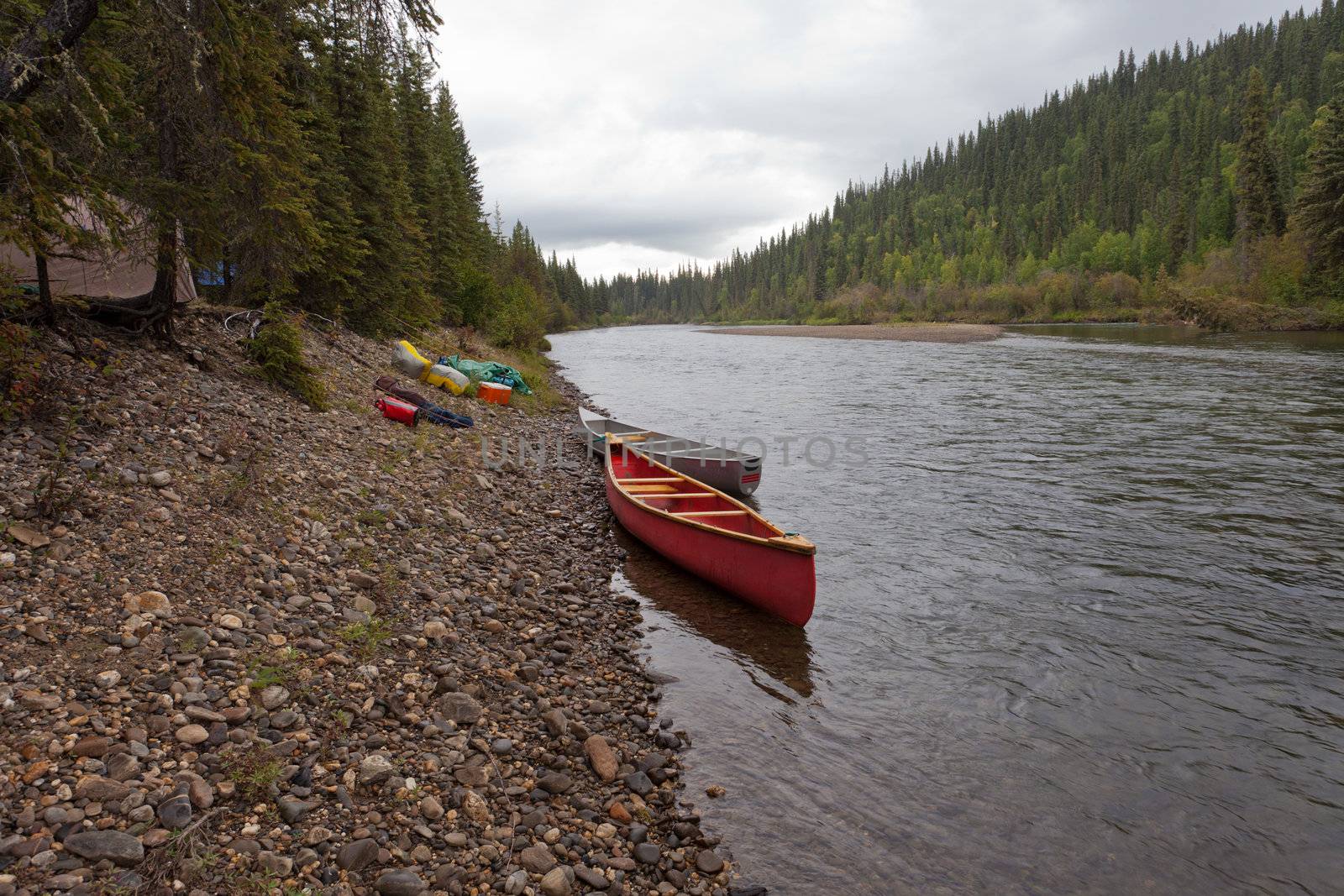 Tent camp in boreal forest and canoes on paddle river trip on McQuesten River, Yukon Territory, Canada