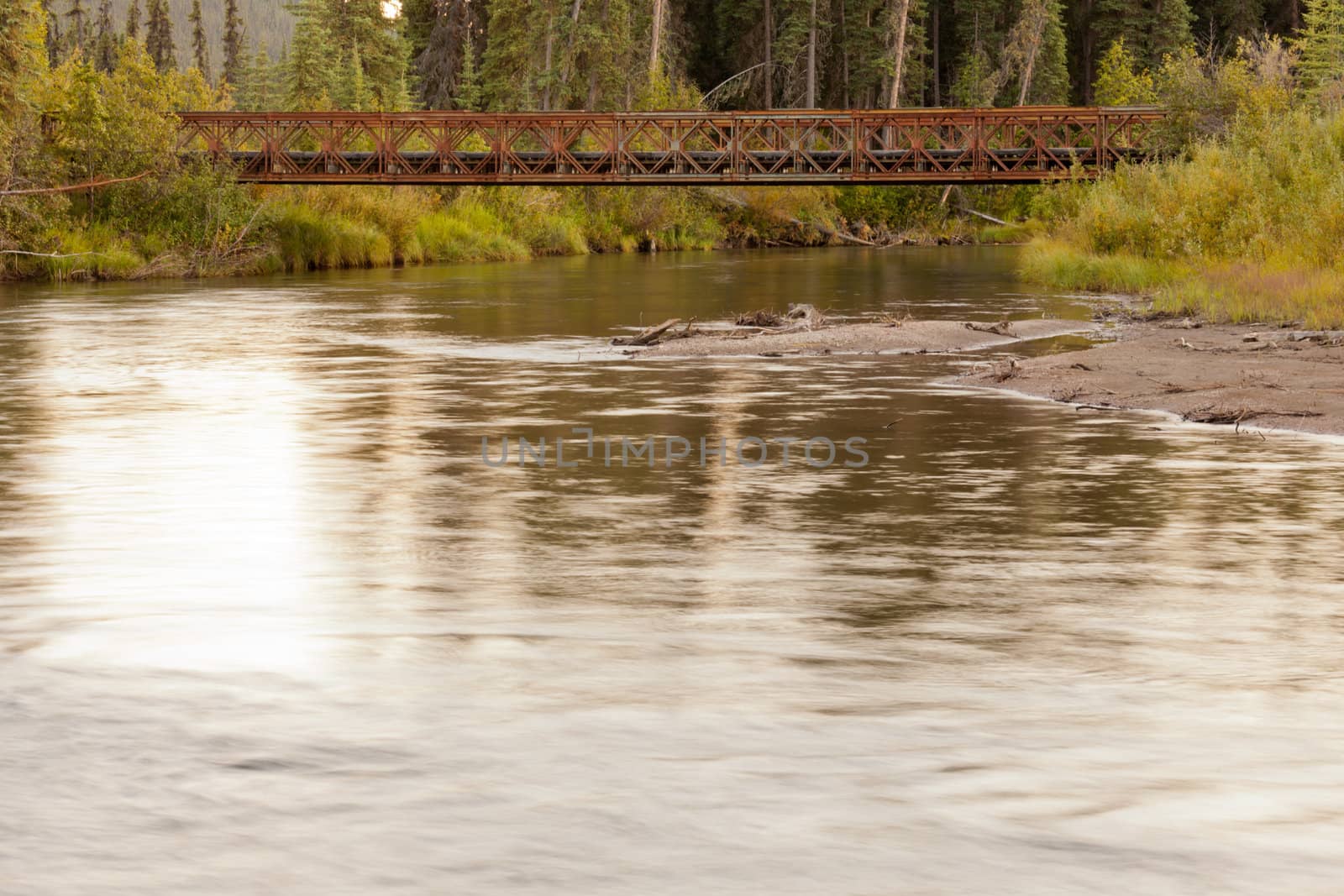 Old rotten abandoned steel bridge across McQuesten River in boreal forest taiga of central Yukon Territory, Canada