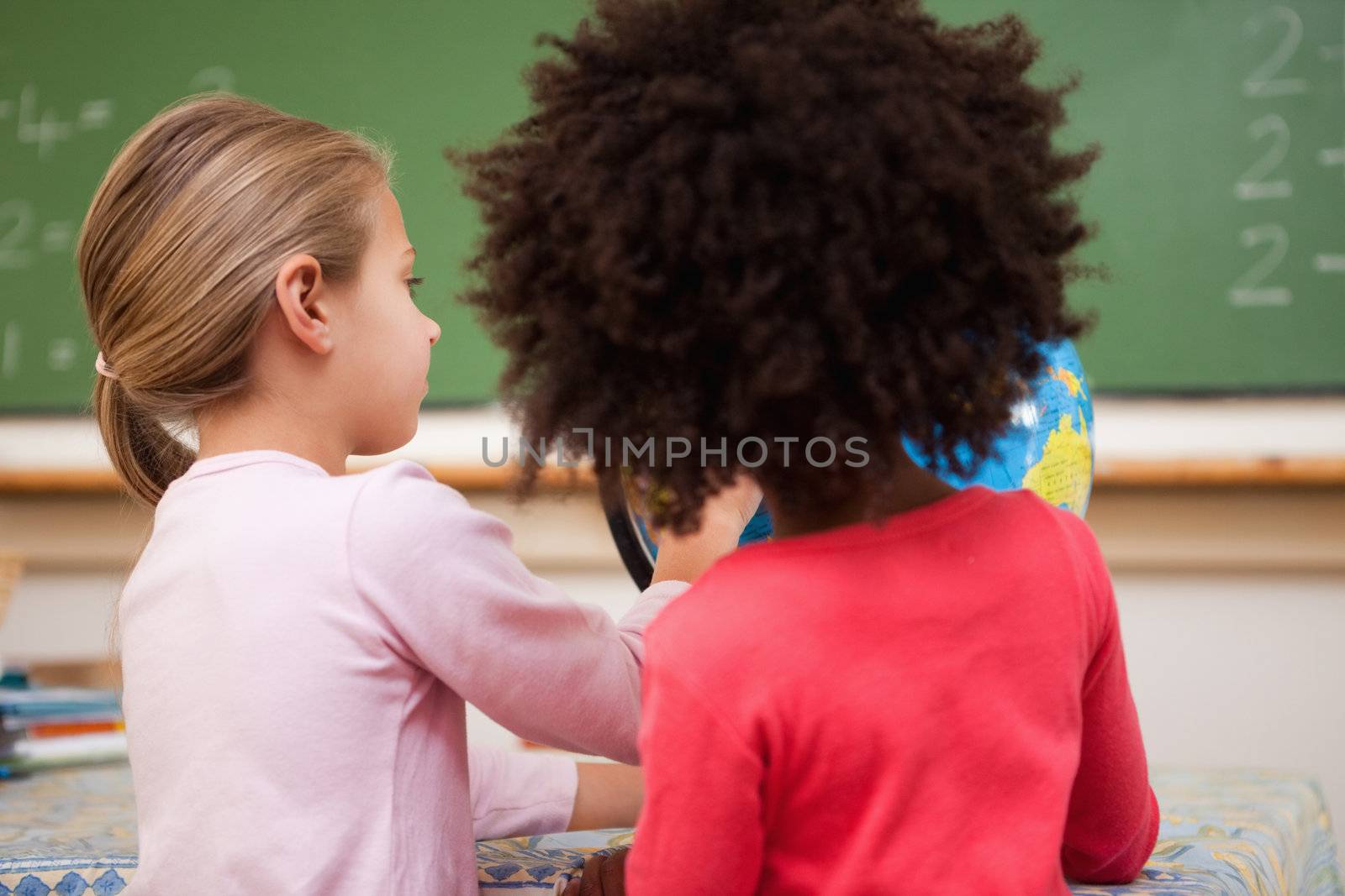 Schoolgirls looking at a globe in a classroom