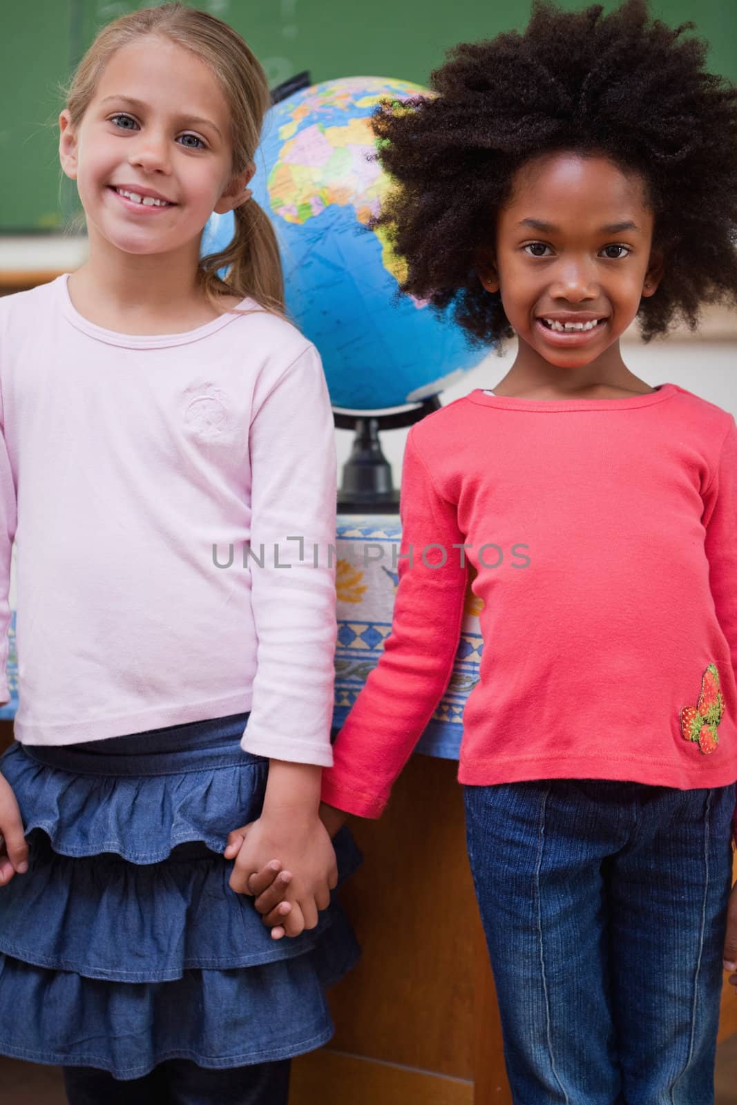 Portrait of schoolgirls holding hands in a classroom