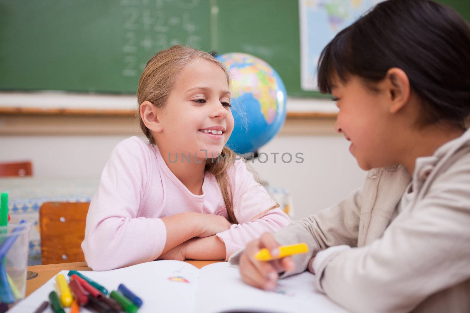 Happy schoolgirls drawing in a classroom