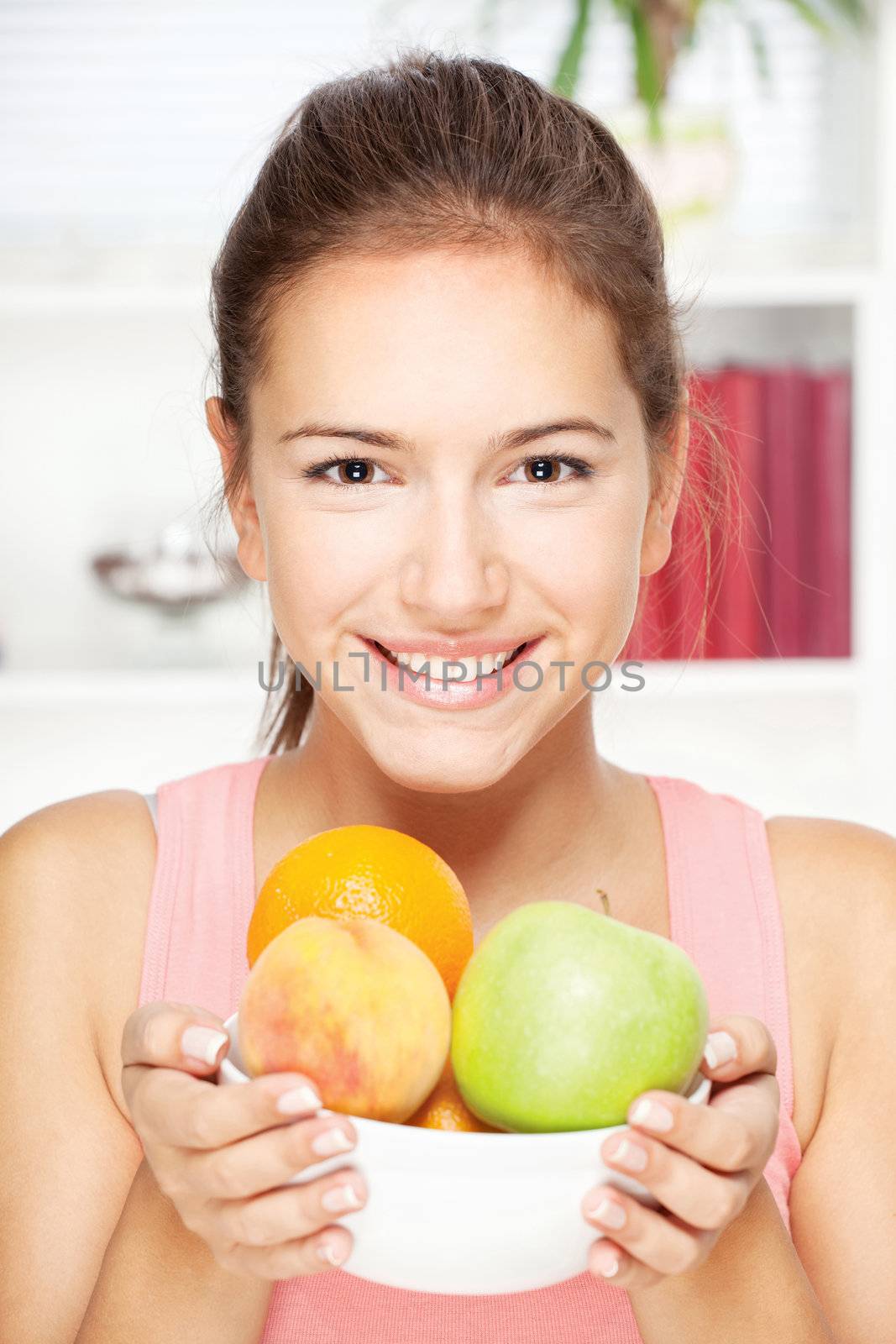 Portrait of young happy smiling woman with bowl of fruits