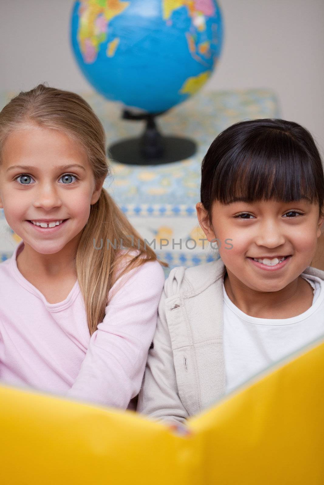 Portrait of happy schoolgirls reading in a classroom