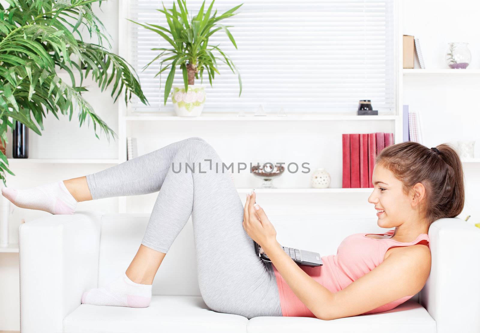 happy woman with laptop lying on the sofa at home