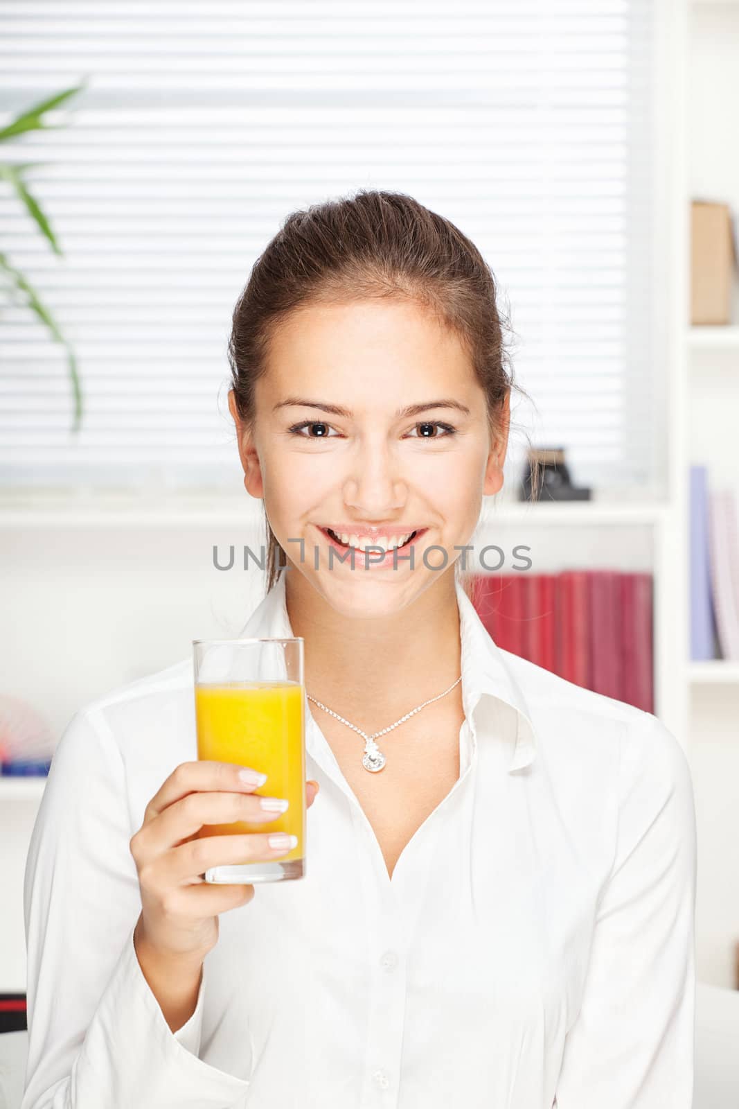 Young smiling woman holding glass of orange juice at home