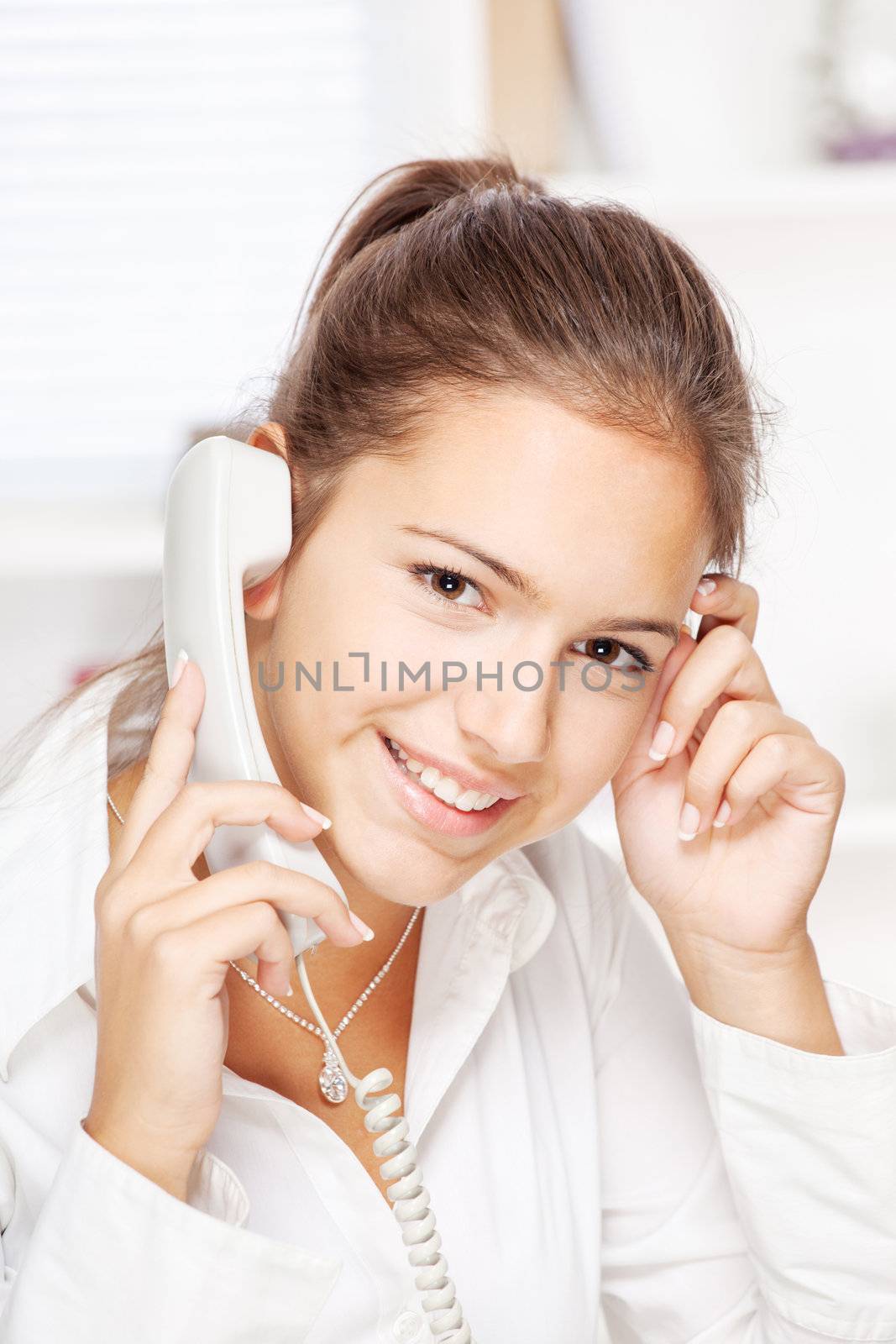 Portrait of office girl on land line call, smiling at camera