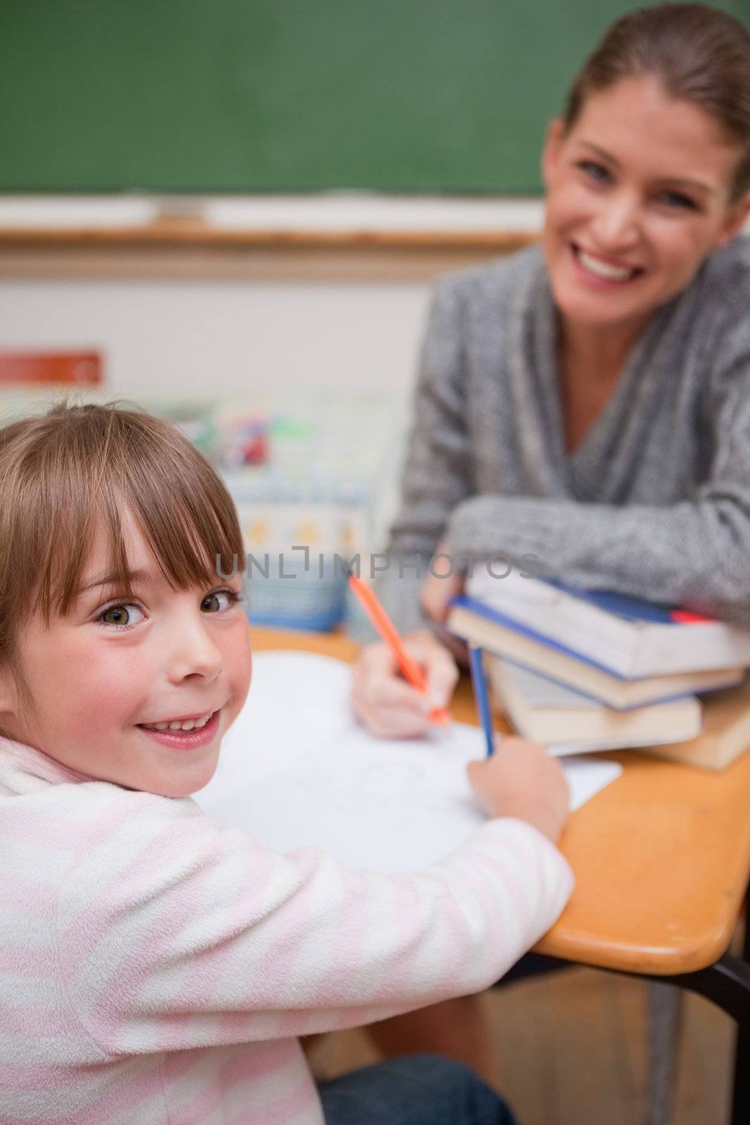 Portrait of a smiling teacher explaining something to her pupil in a classroom